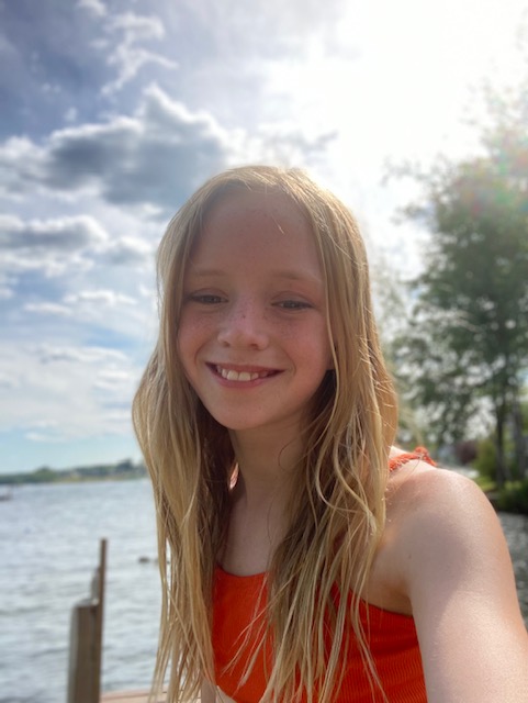 image of young girl outside in front of water in red tank top