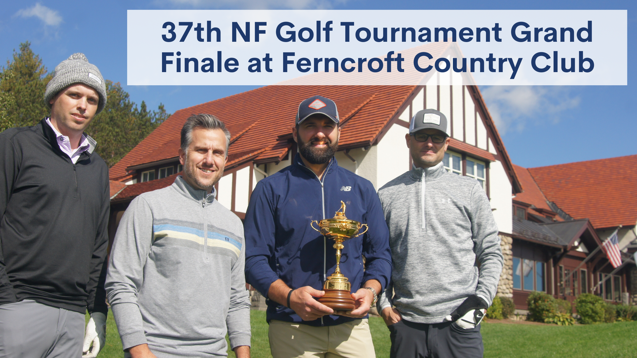 four men standing on a golf course holding a trophy on a sunny day