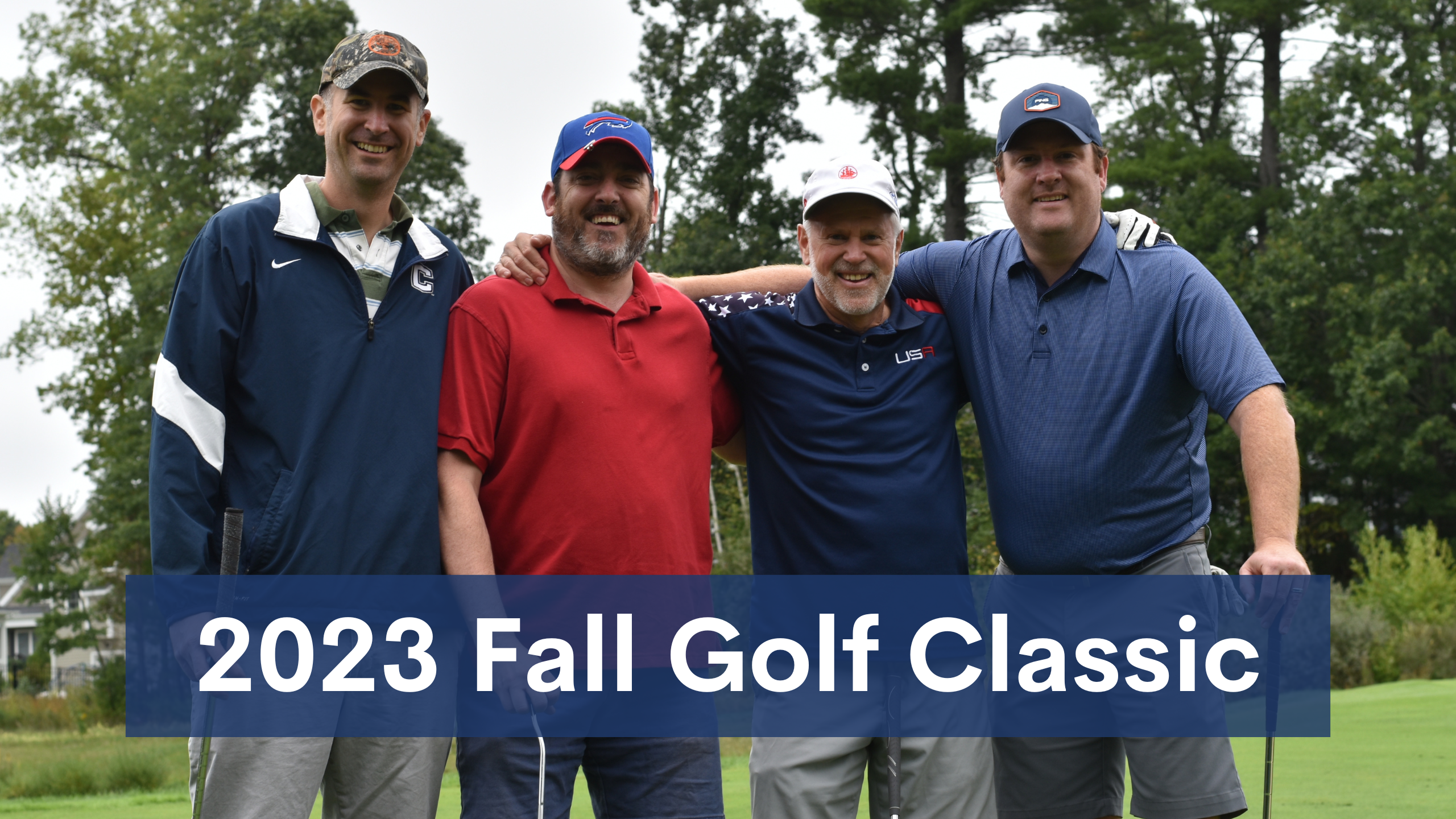 four men in golf-wear smiling with their arms around each other on a golf course