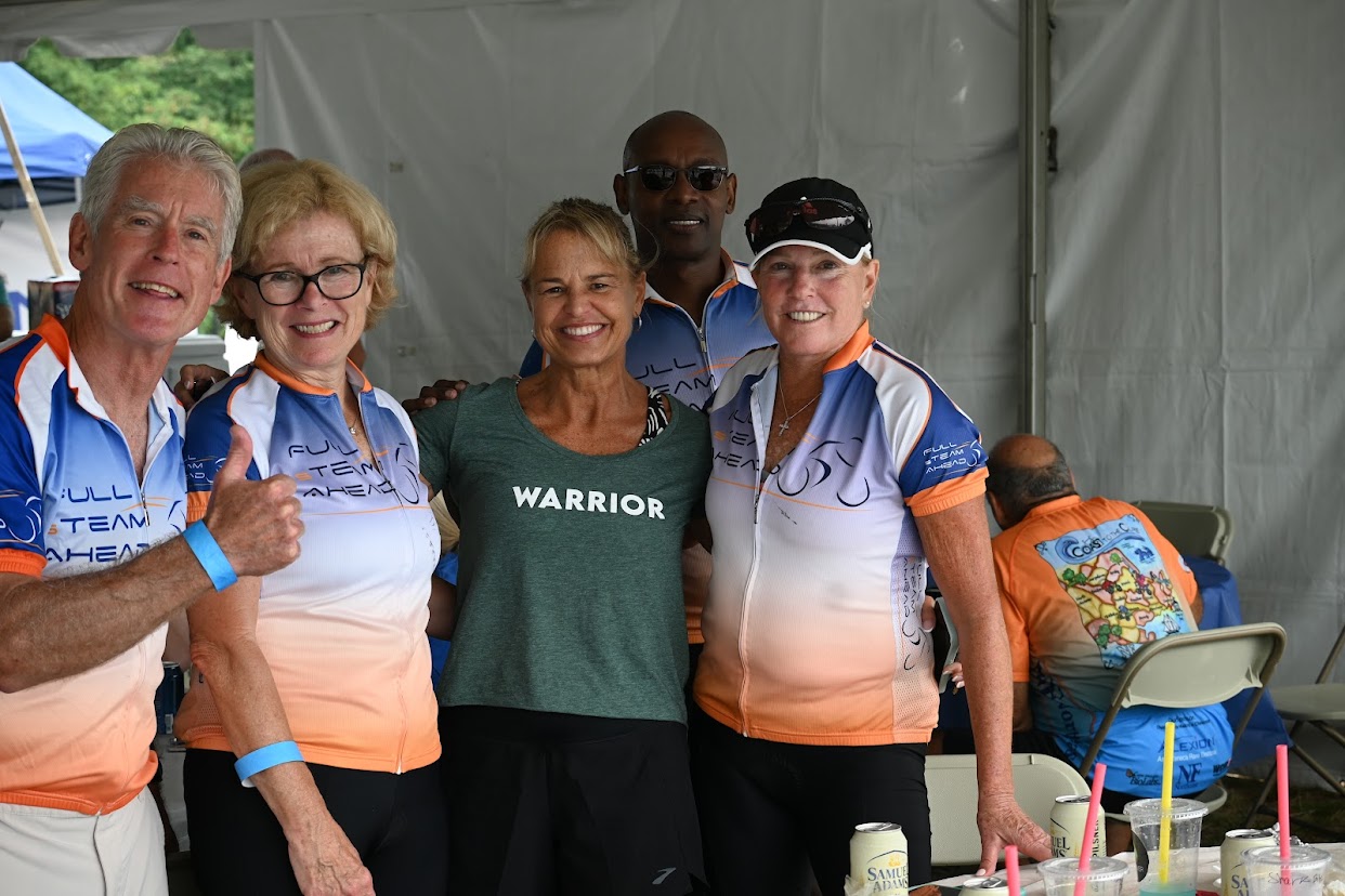 5 cyclists standing with their arms around each other in the beer garden tent after a race