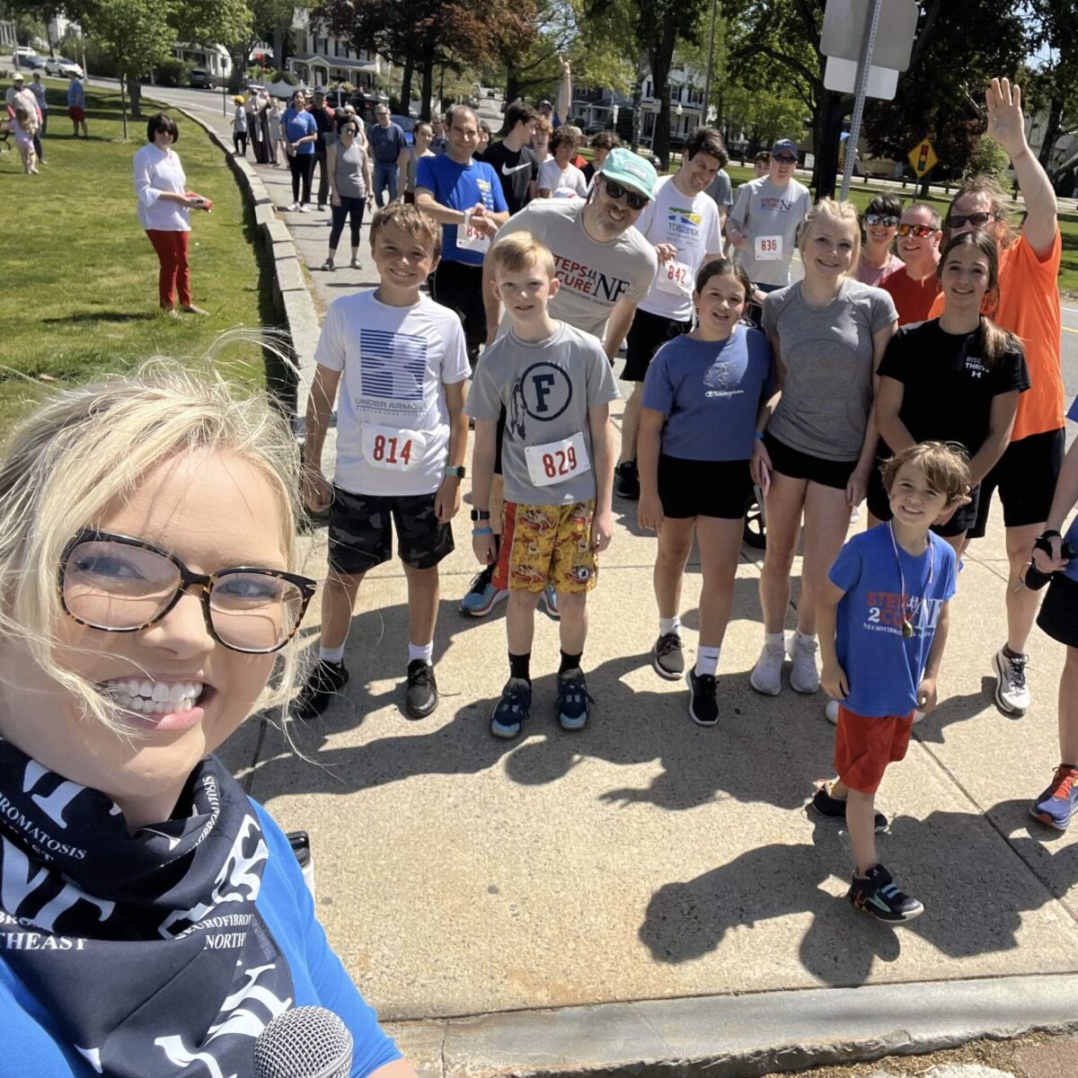 woman in NF Northeast bandana taking a selfie with walk participants on the route behind her