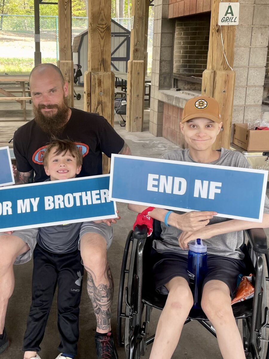 man holding little boy with sign that reads "For My Brother" (left); boy in wheelchair wearing a Boston Bruins hat holding a sign that reads "End NF" (right)
